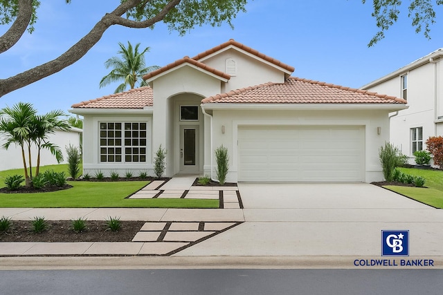 mediterranean / spanish house featuring an attached garage, a front lawn, a tile roof, stucco siding, and concrete driveway