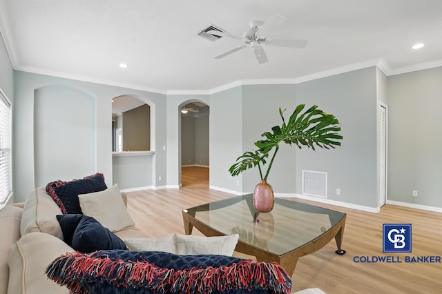 living area featuring visible vents, arched walkways, crown molding, and wood finished floors