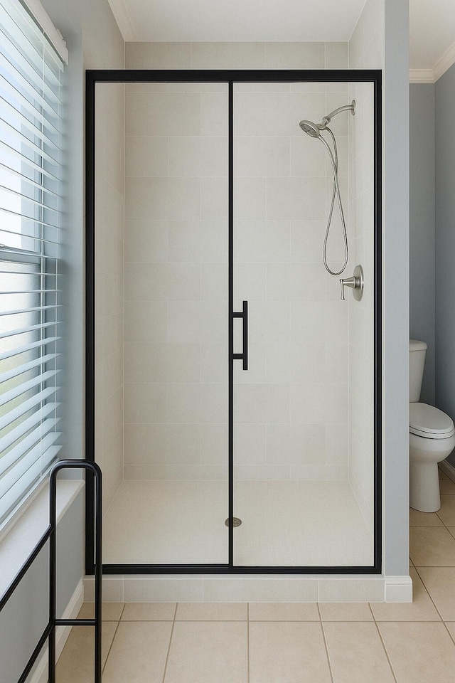bathroom with crown molding, tile patterned floors, a shower stall, and toilet