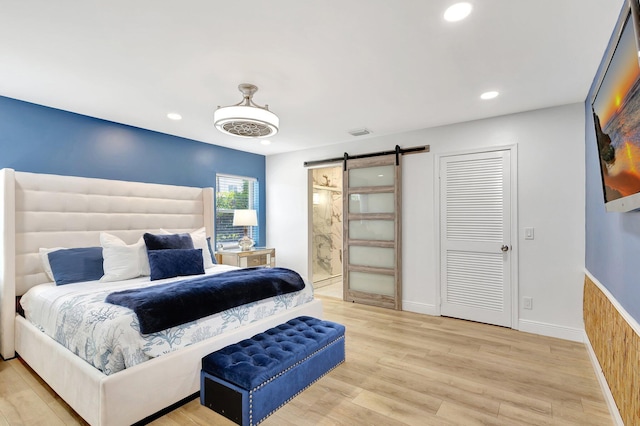 bedroom featuring light wood-type flooring, recessed lighting, visible vents, and a barn door