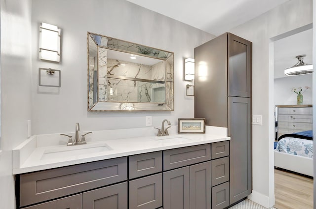ensuite bathroom featuring double vanity, a marble finish shower, a sink, and connected bathroom
