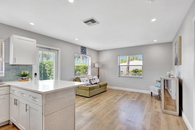 kitchen with visible vents, white cabinets, light wood-style floors, and baseboards