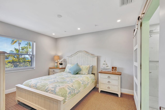 bedroom with a barn door, visible vents, baseboards, and carpet floors
