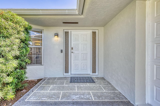 doorway to property featuring stucco siding