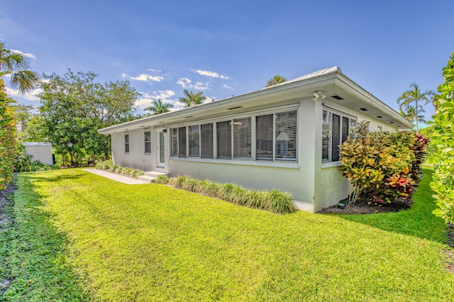 rear view of property with a yard, entry steps, and stucco siding