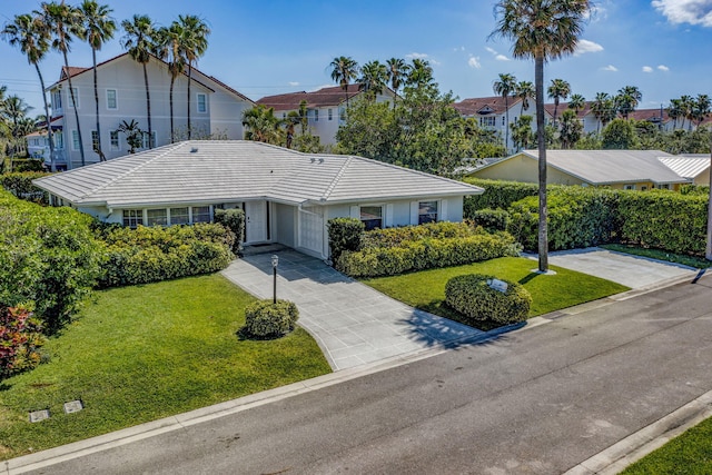 single story home featuring a front yard, a tiled roof, a carport, and driveway