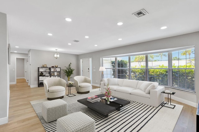 living room with baseboards, visible vents, and light wood-style flooring