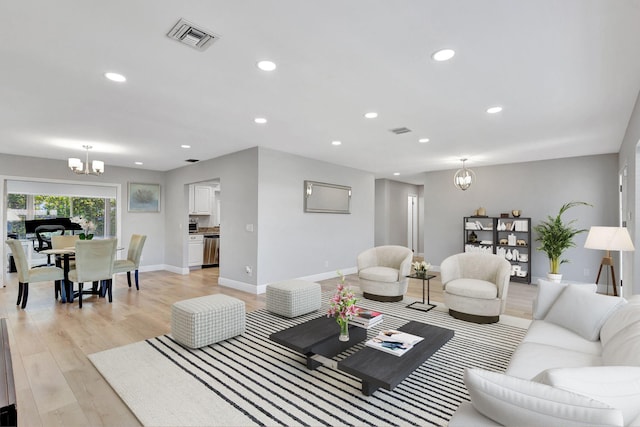 living room with baseboards, recessed lighting, visible vents, light wood-style floors, and a chandelier
