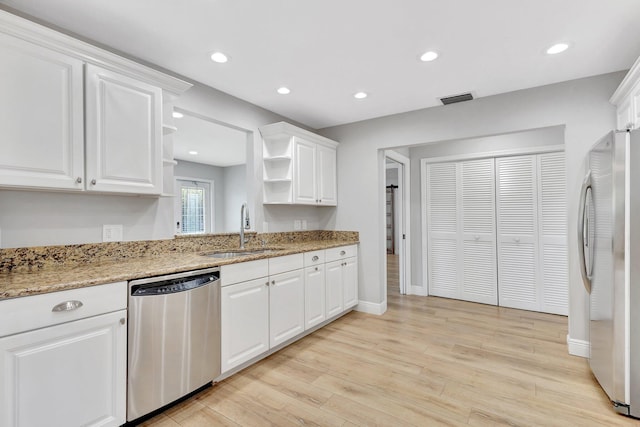 kitchen with appliances with stainless steel finishes, a sink, open shelves, and white cabinets
