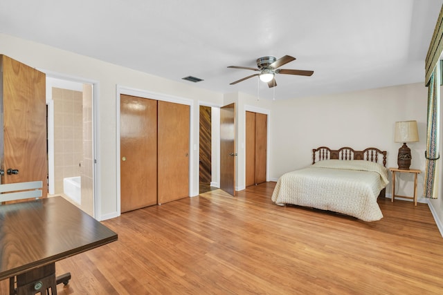 bedroom featuring baseboards, light wood-style floors, multiple closets, and visible vents