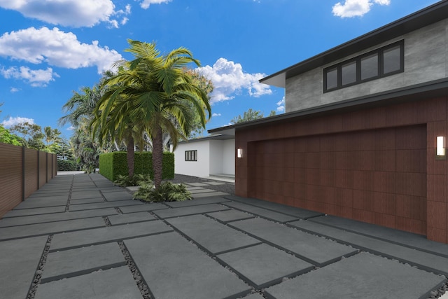 exterior space featuring stucco siding, fence, and a garage