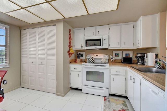 25 Abbey Ln Unit 404, Delray Beach, FL 33446 - kitchen with white appliances, a sink, light countertops, light tile patterned flooring, and white cabinetry