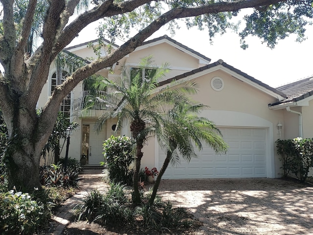 view of front of house featuring a tiled roof, driveway, stucco siding, and an attached garage