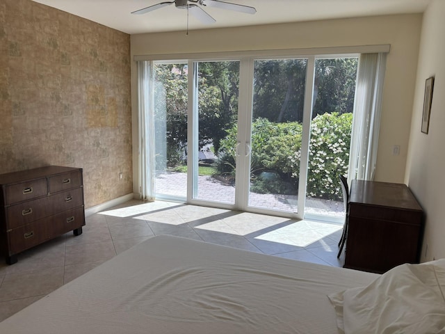 tiled bedroom with baseboards, access to exterior, ceiling fan, and multiple windows