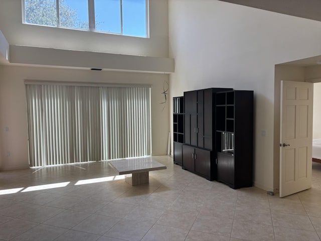 interior space featuring baseboards, a high ceiling, and light tile patterned floors