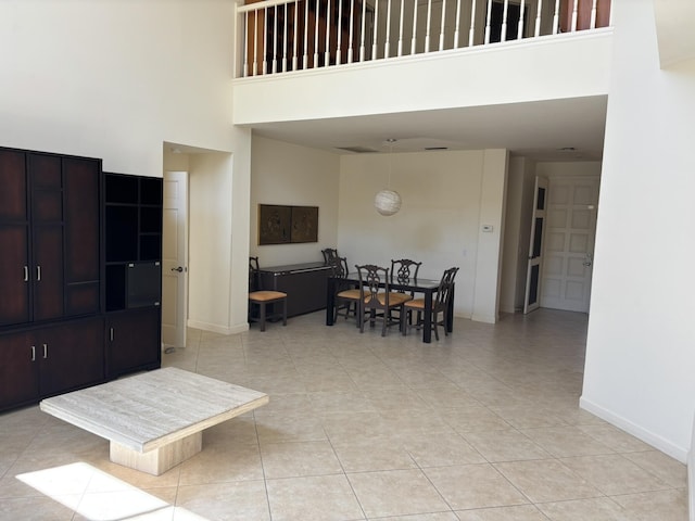 living room with a high ceiling, light tile patterned flooring, and baseboards