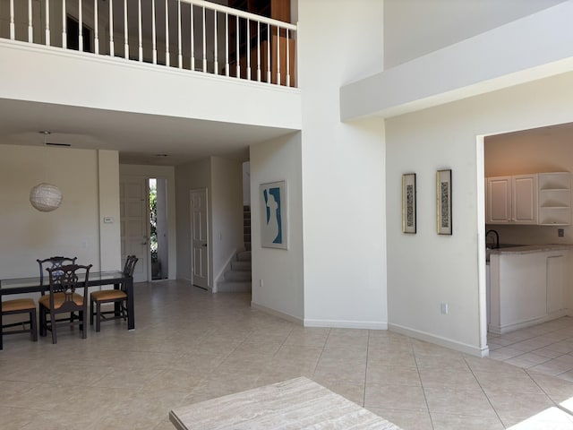 interior space featuring light tile patterned floors, baseboards, a towering ceiling, and stairway