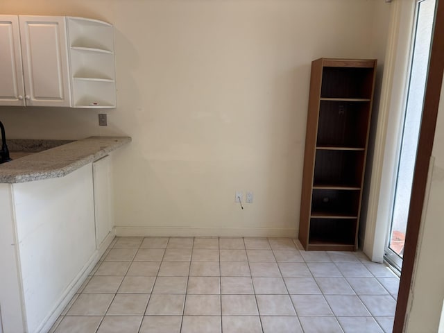 unfurnished dining area featuring baseboards and light tile patterned flooring