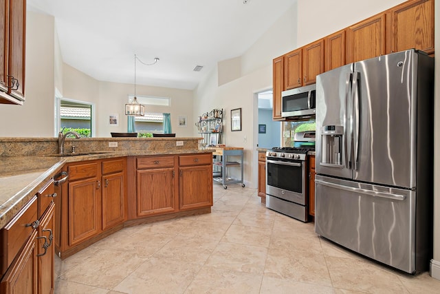 1167 Egret Cir S, Jupiter, FL 33458 - kitchen with stainless steel appliances, brown cabinetry, hanging light fixtures, and a peninsula