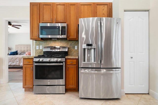 1167 Egret Cir S, Jupiter, FL 33458 - kitchen with appliances with stainless steel finishes, a ceiling fan, brown cabinets, tasteful backsplash, and light tile patterned floors