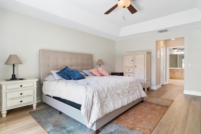 1167 Egret Cir S, Jupiter, FL 33458 - bedroom with light wood finished floors, a tray ceiling, ensuite bath, and ceiling fan