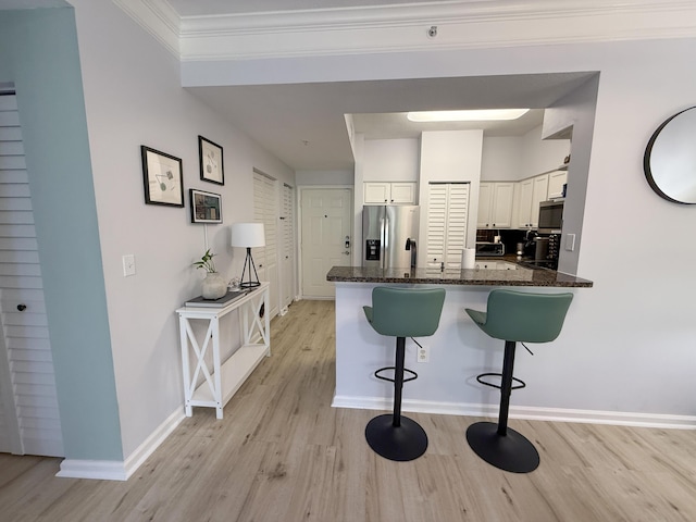 275 Murcia Dr Unit 304, Jupiter, FL 33458 - kitchen with stainless steel appliances, light wood-type flooring, a breakfast bar area, white cabinets, and a peninsula