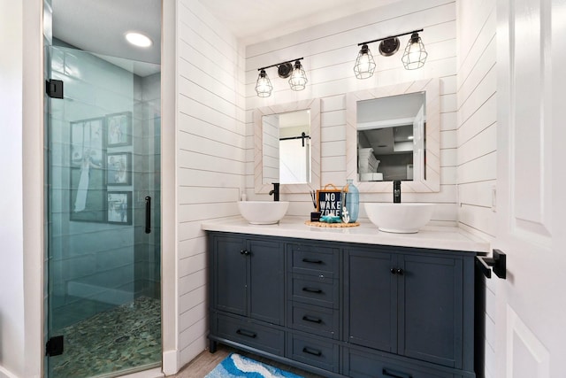 full bathroom featuring a stall shower, double vanity, and a sink