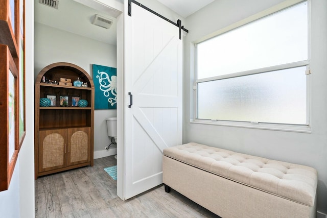 living area featuring visible vents, light wood finished floors, and a barn door
