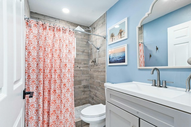 full bath featuring toilet, a tile shower, and vanity