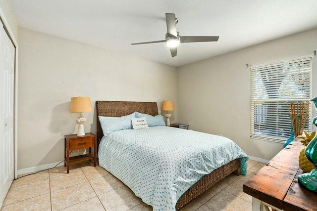 bedroom with ceiling fan, a closet, light tile patterned flooring, and baseboards