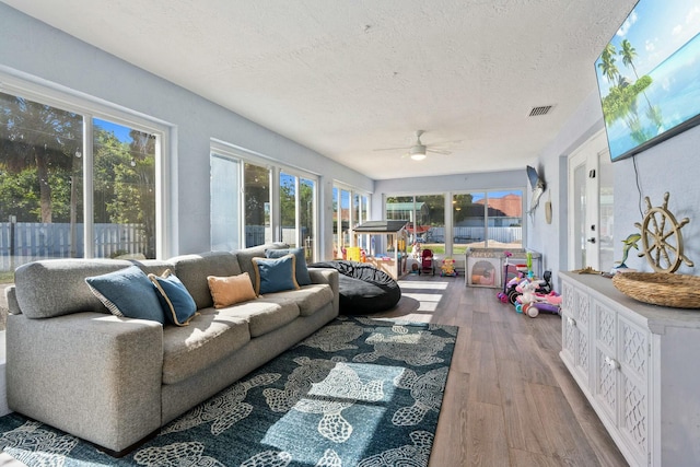 sunroom / solarium featuring a healthy amount of sunlight, a textured ceiling, and wood finished floors