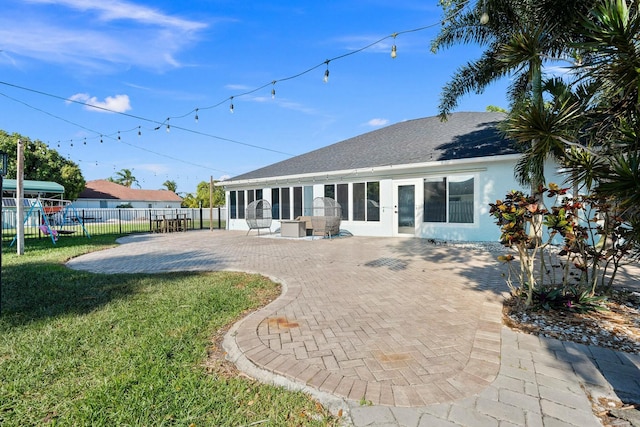 rear view of property with a yard, stucco siding, a patio, fence, and french doors