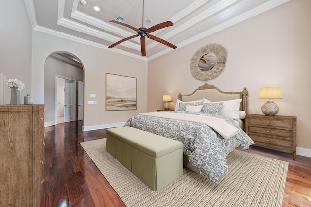 bedroom featuring visible vents, ornamental molding, wood finished floors, a tray ceiling, and arched walkways