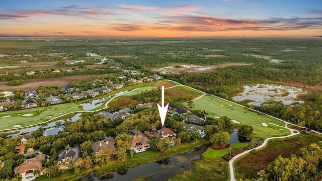 aerial view at dusk with a water view, golf course view, and a residential view