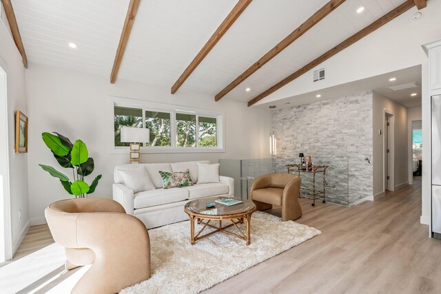 living area with beamed ceiling, visible vents, and light wood-type flooring