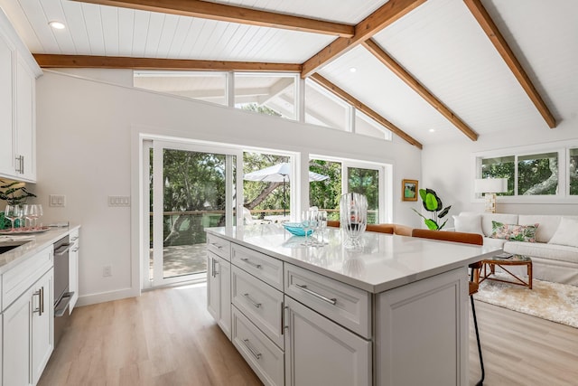 kitchen with open floor plan, lofted ceiling with beams, a healthy amount of sunlight, and light wood-style floors