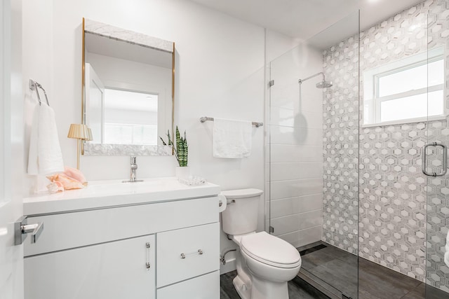 full bath with a tile shower, toilet, and vanity