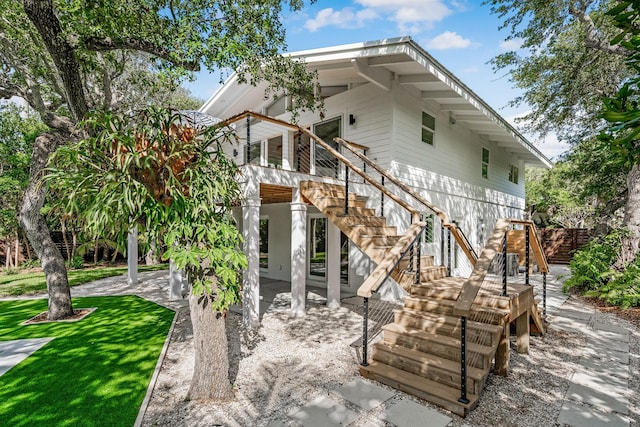 rear view of property featuring a wooden deck, stairway, a yard, and a patio
