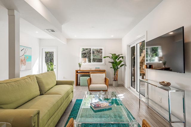 living room featuring recessed lighting, plenty of natural light, visible vents, and wood finished floors