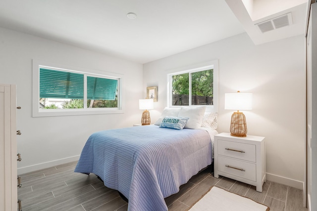 bedroom with wood finish floors, visible vents, and baseboards