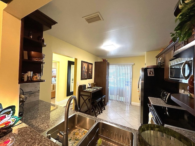 4330 Lucerne Villas Ln, Lake Worth, FL 33467 - kitchen with visible vents, dark brown cabinets, stainless steel microwave, a sink, and light tile patterned floors
