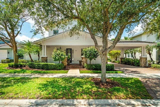 view of front of house featuring decorative driveway, a porch, a front lawn, and an attached carport