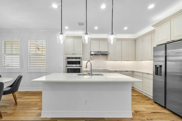 kitchen with a sink, appliances with stainless steel finishes, under cabinet range hood, and light countertops