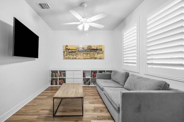 living room featuring baseboards, visible vents, wood finished floors, and ceiling fan