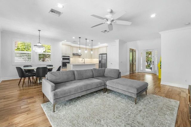 living room with crown molding, a ceiling fan, baseboards, and plenty of natural light