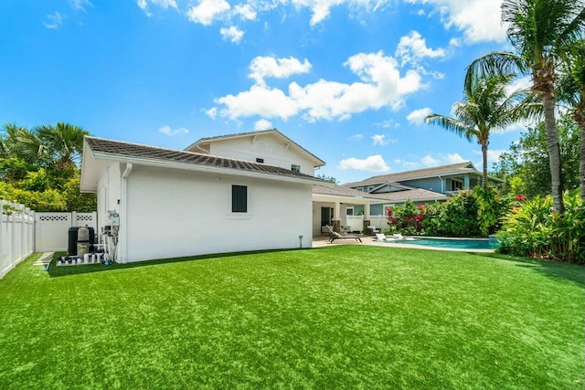 rear view of house featuring stucco siding, a yard, and a fenced backyard