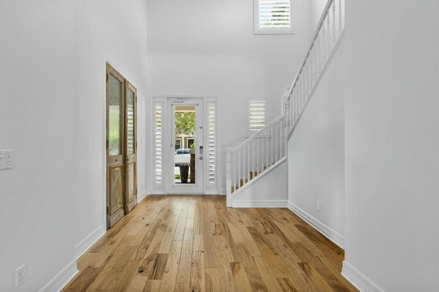entrance foyer featuring a towering ceiling, stairway, hardwood / wood-style flooring, and baseboards