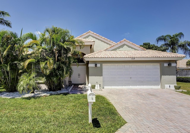 mediterranean / spanish-style home featuring decorative driveway, an attached garage, a front yard, and stucco siding