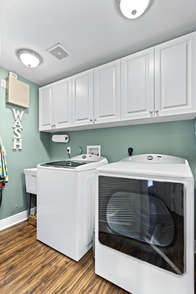 laundry room featuring cabinet space, dark wood-style floors, baseboards, visible vents, and washing machine and dryer