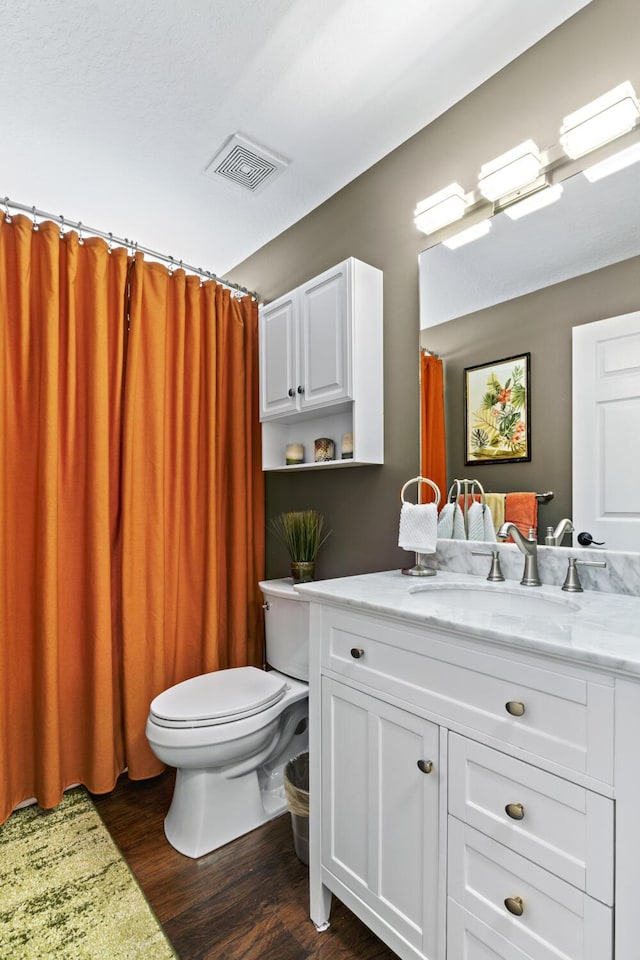 bathroom featuring visible vents, wood finished floors, toilet, and vanity